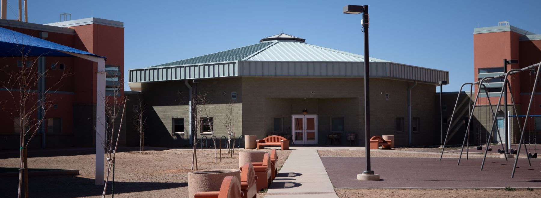 School courtyard with swing set and lots of benches to sit and relax.