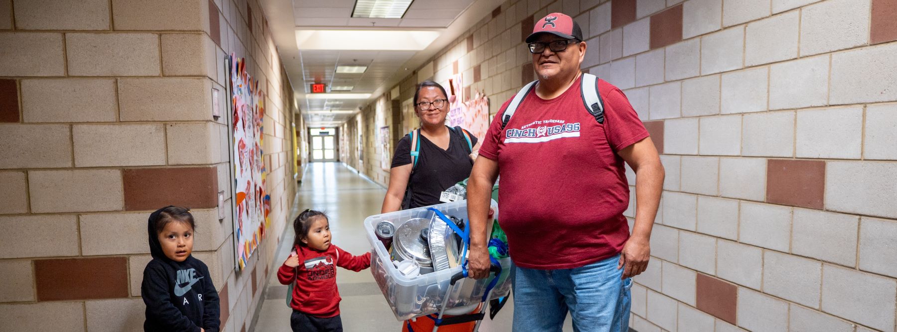 A man and woman are positioned in a hallway with two children, creating a warm family atmosphere.
